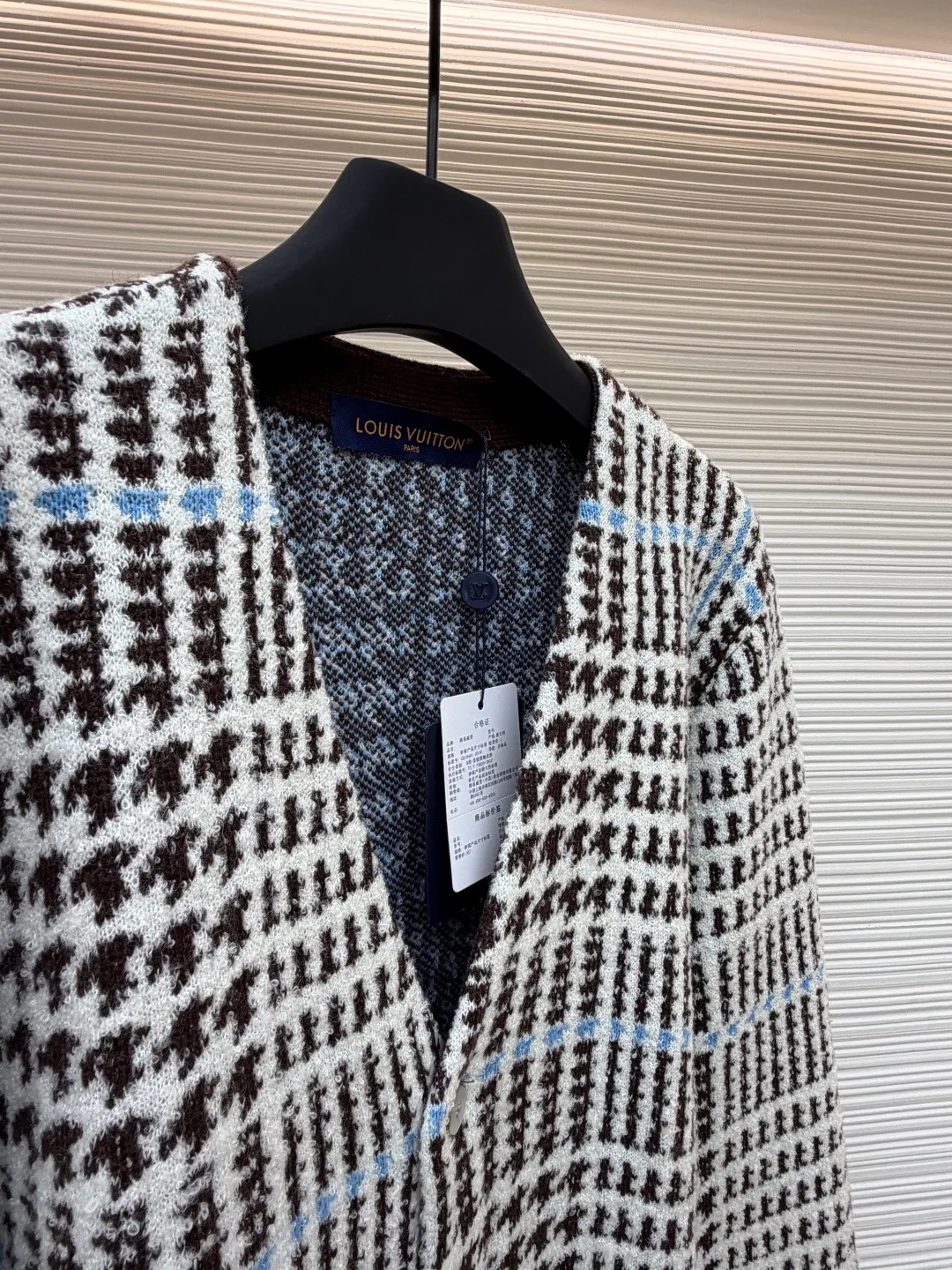 LOUIS VUITTON letter intarsia houndstooth knitted jacquard cardigan ●Original version: purchased and developed by 14743 ●Item number: 1681873-C00 ●Fabric: wool blended fabric ●Technology: jacquard knitting ●Color: black, white and blue ●Version: fitted version ●Weight: about 695 grams ●Size: S-M-L-XL ●Description: The main pattern of this cardigan is woven with full-width jacquard technology, using 69% sheep wool blended with 31% nylon yarn to interweave the houndstooth pattern with light blue line texture. At the same time, the brand logo elements are integrated into the body through intarsia technology, and the edges of the pattern are connected delicately and seamlessly. The collar, cuffs and hem are made of 100% sheep wool ribbed fabric, and are edged with double-needle seaming technology, which has both elasticity and shaping effect. The front placket is equipped with natural-textured buttons, and the side seam pockets use invisible stitching technology to blend naturally with the jacquard texture of the body. The overall shape is shaped through three-dimensional tailoring, and the shoulders are stitched with seamless stitching to ensure fit and comfort. The entire piece is finished with handcrafted details in an Italian workshop, showing the craftsmanship precision of high-quality knitted items. The overall wiring is straight and delicate, the fabric is comfortable and soft, and the color is consistent without color difference. It can be matched with the same style to create a fashionable look and control various occasions. Customized accessories, complete with three standards, same style for men and women!